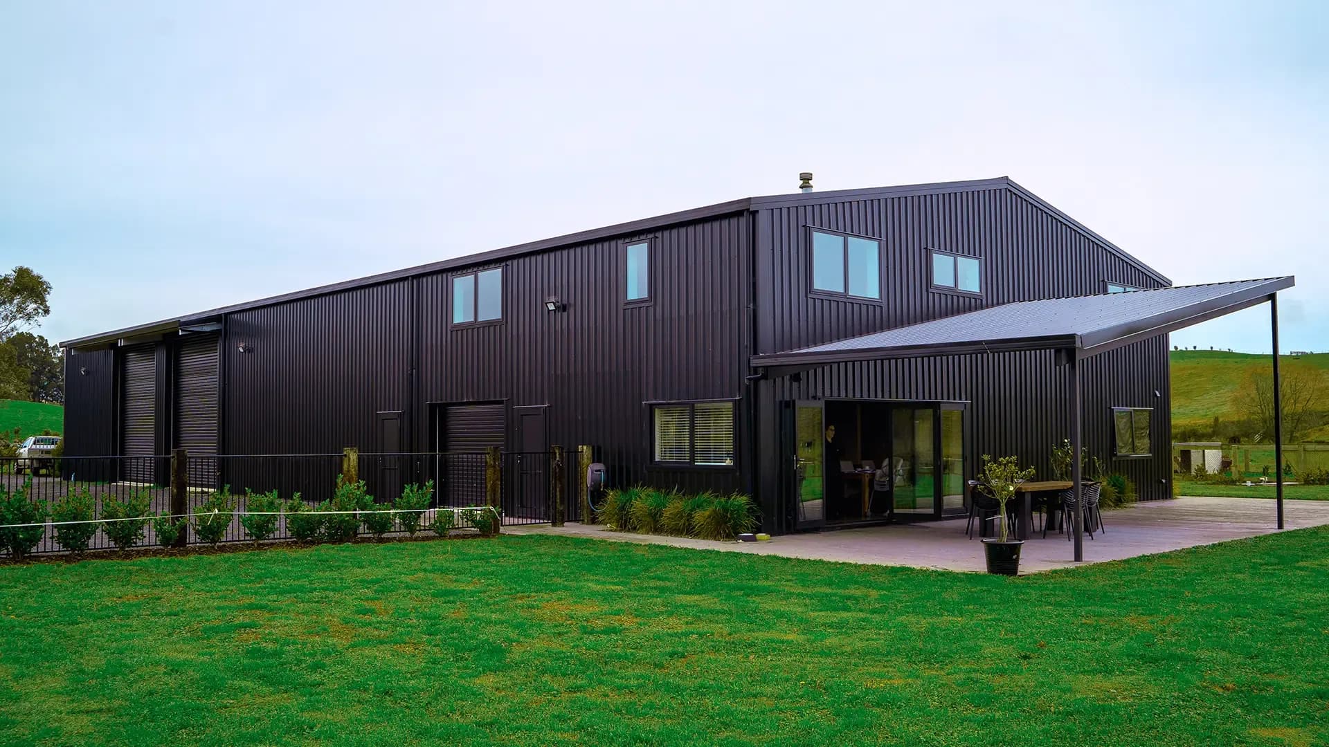 Black-clad two-storey shed house with covered outdoor living, Waikato