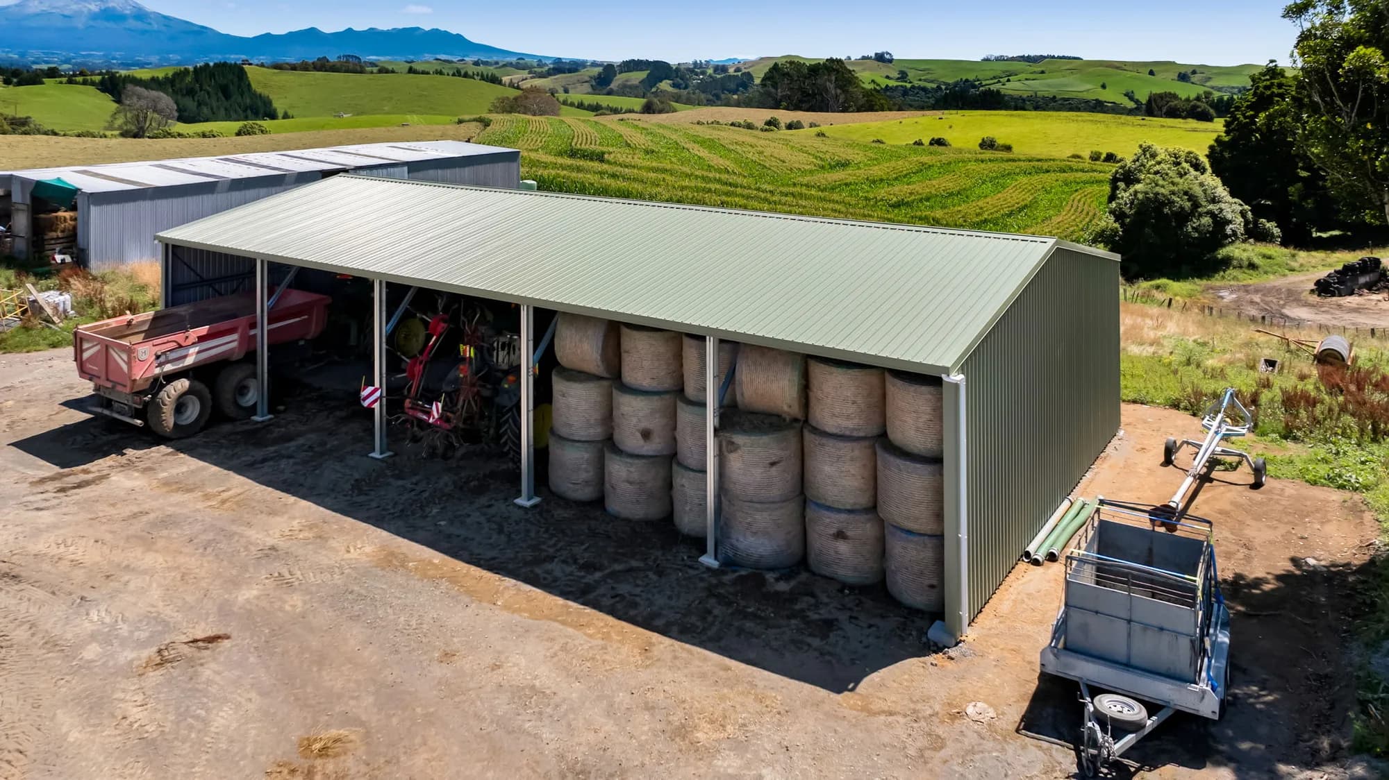 Open-bay rural shed storing hay bales and farm machinery, Taranaki